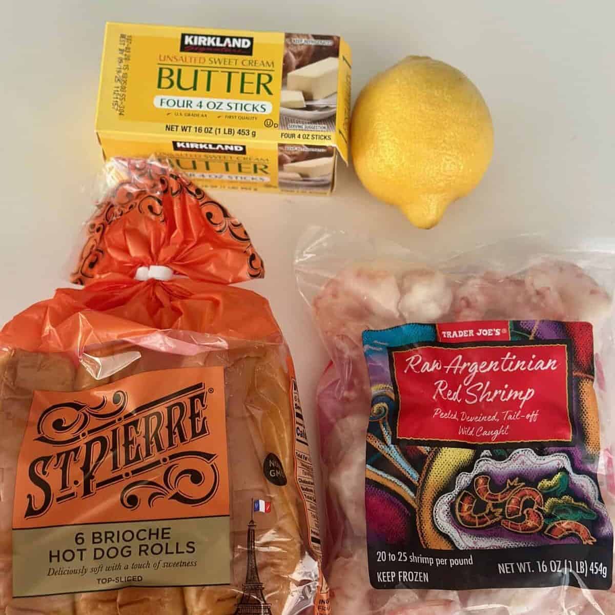 Ingredients for butter poached shrimp rolls including buns, shrimp, butter, and lemon.