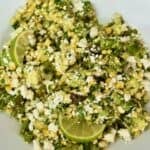 Bowl of charred corn salad with shishito peppers, avocado, queso fresco, cilantro, and lime.