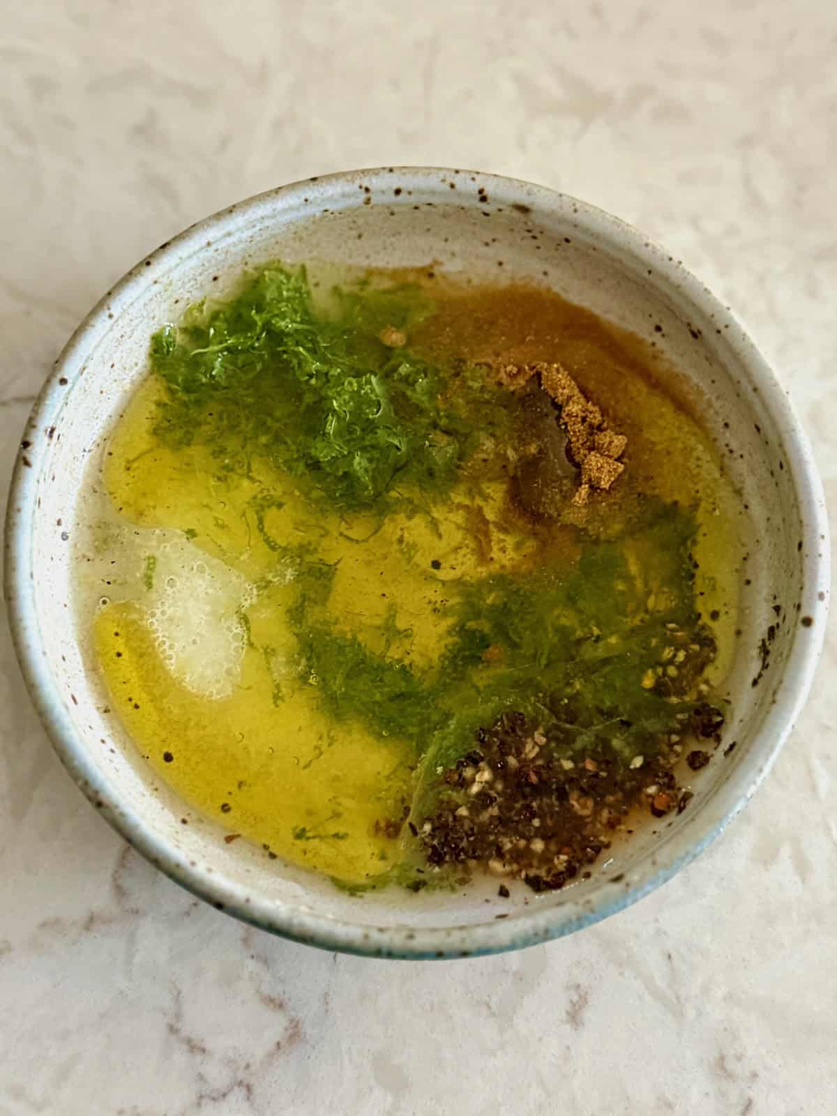 Lime juice, olive oil, cumin, salt, pepper, and lime zest whisked together in a bowl.