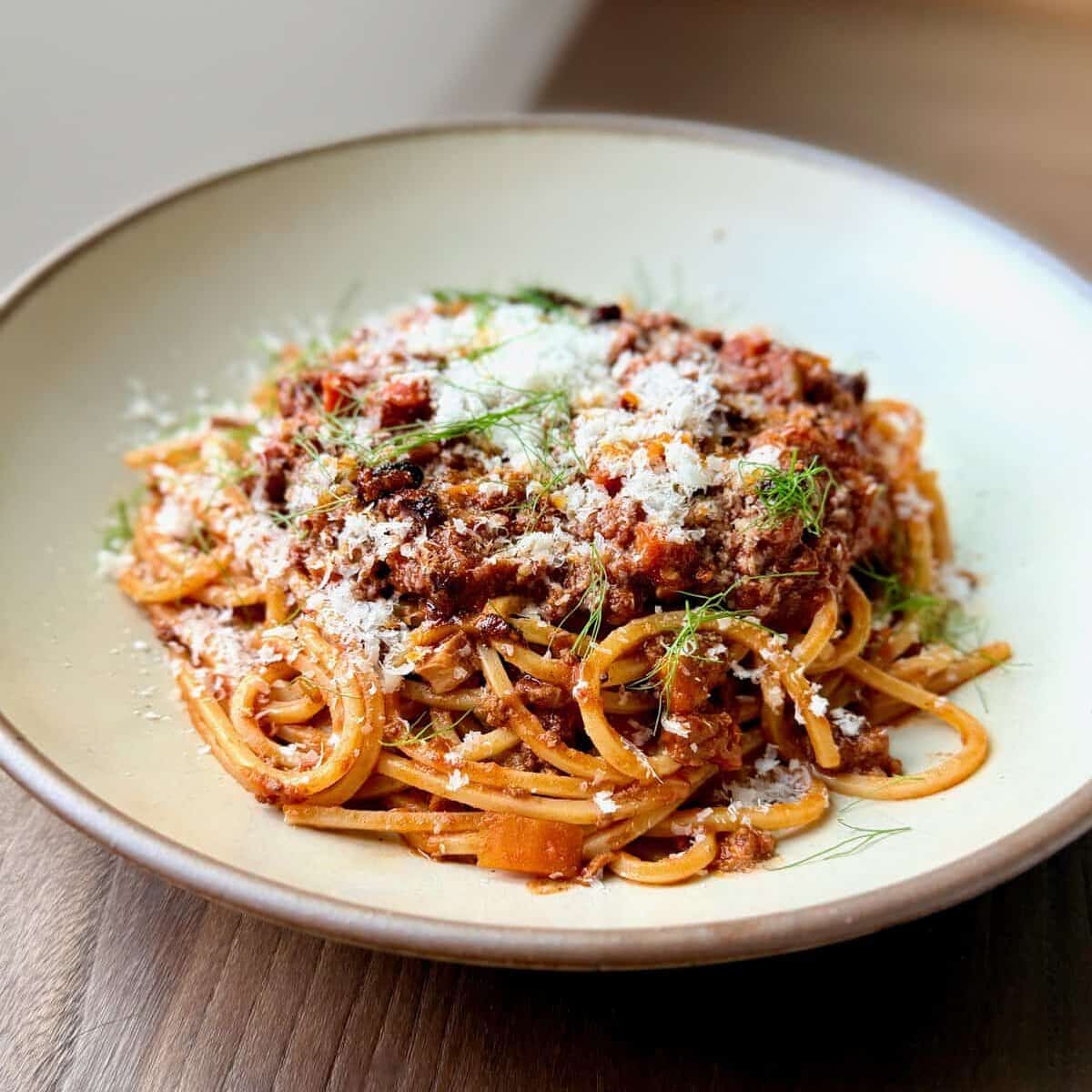 Chinese-Italian Ragu with spaghetti is topped with Parmesan and fennel fronds.