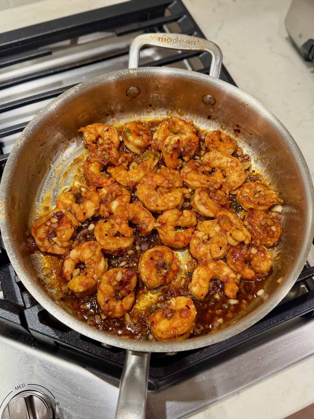 Cooked shrimp are tossed in the thickened garlic butter sauce in the pan.