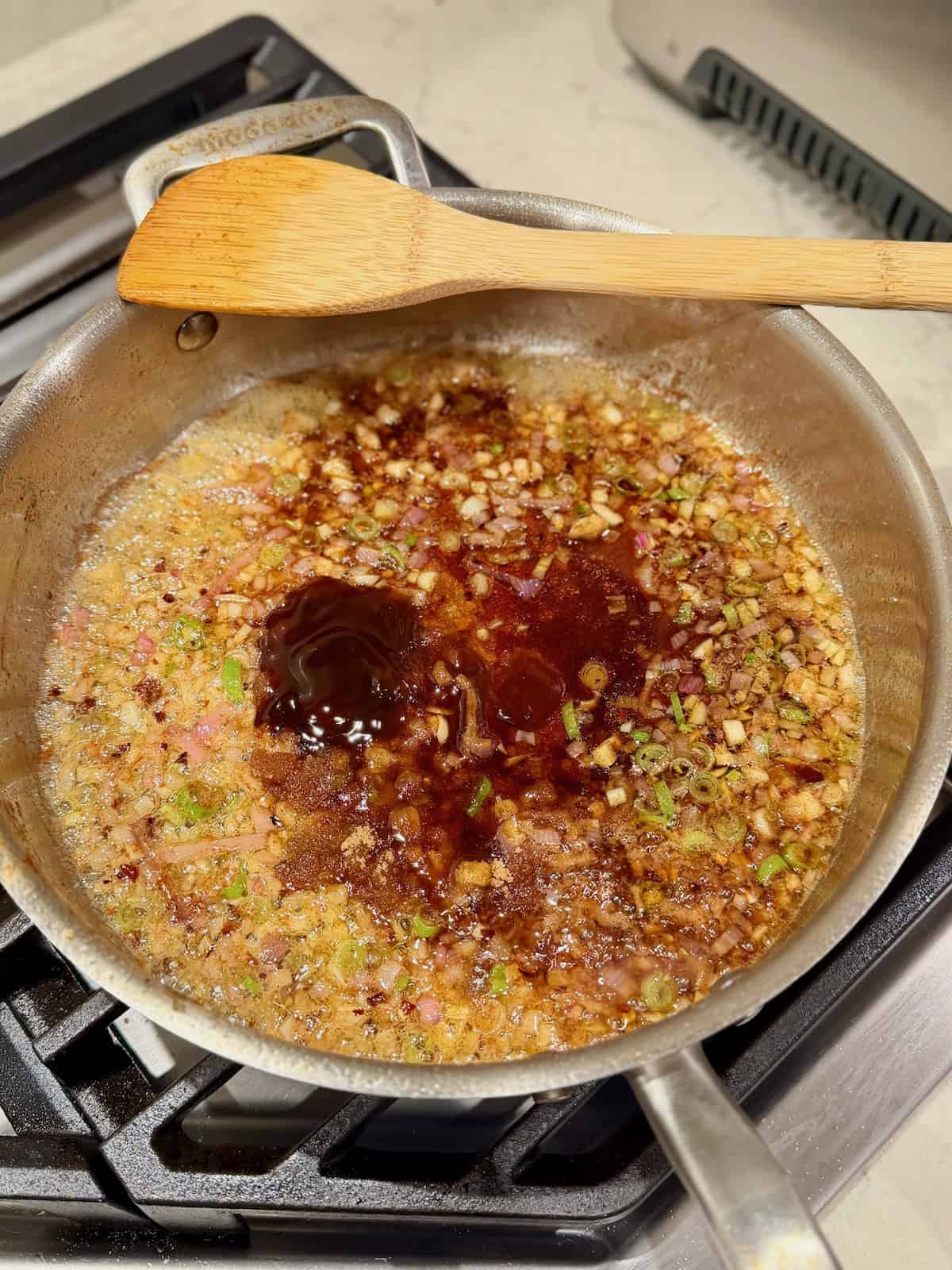 Soy sauce, oyster sauce, fish sauce, and brown sugar are added to the aromatics.