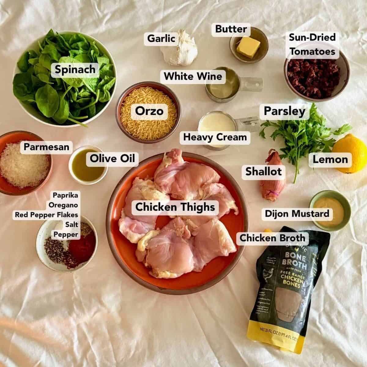 Ingredients for chicken orzo include chicken thighs, orzo, spinach, sun-dried tomatoes, Parmesan, cream, and aromatics.