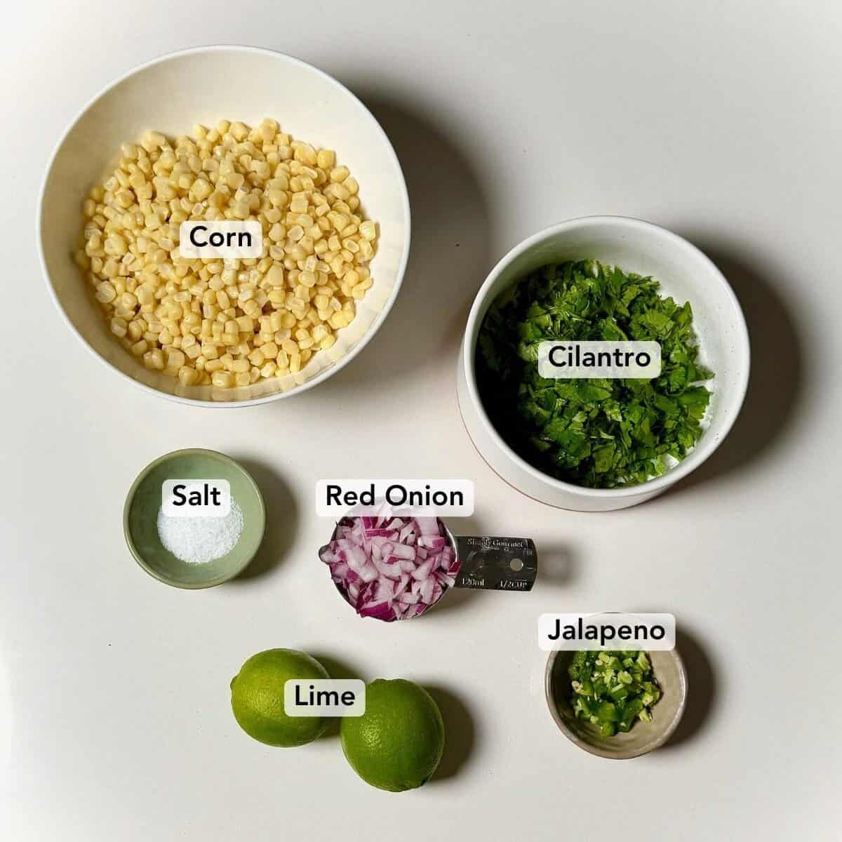 Ingredients for chipotle copycat corn salsa including corn, cilantro, red onion, lime, jalapeno, and salt.