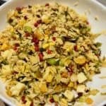 Warm fall orzo salad in a white bowl with roasted delicata squash, Brussels sprouts, cubes of white cheddar, crispy pancetta, and red pomegranate seeds.